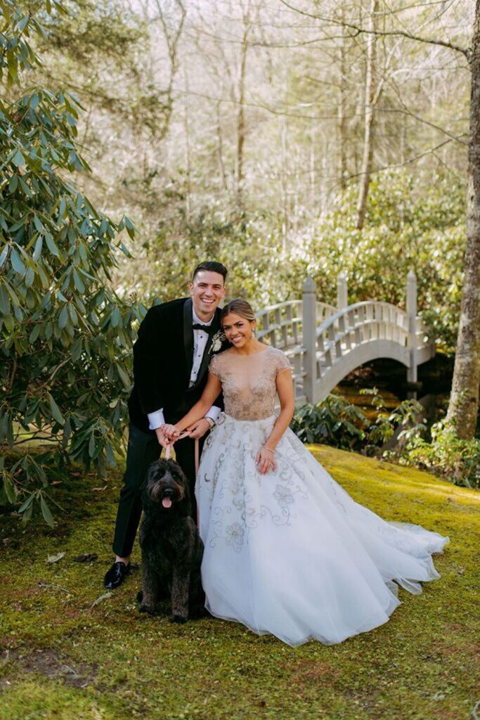 Bride and Groom smiling with their dog on their wedding day