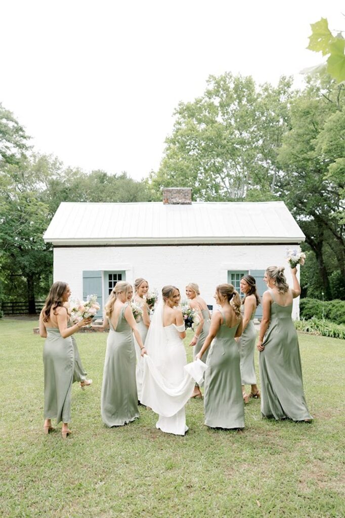 Bridesmaids celebrating with bride and fluffing her wedding dress