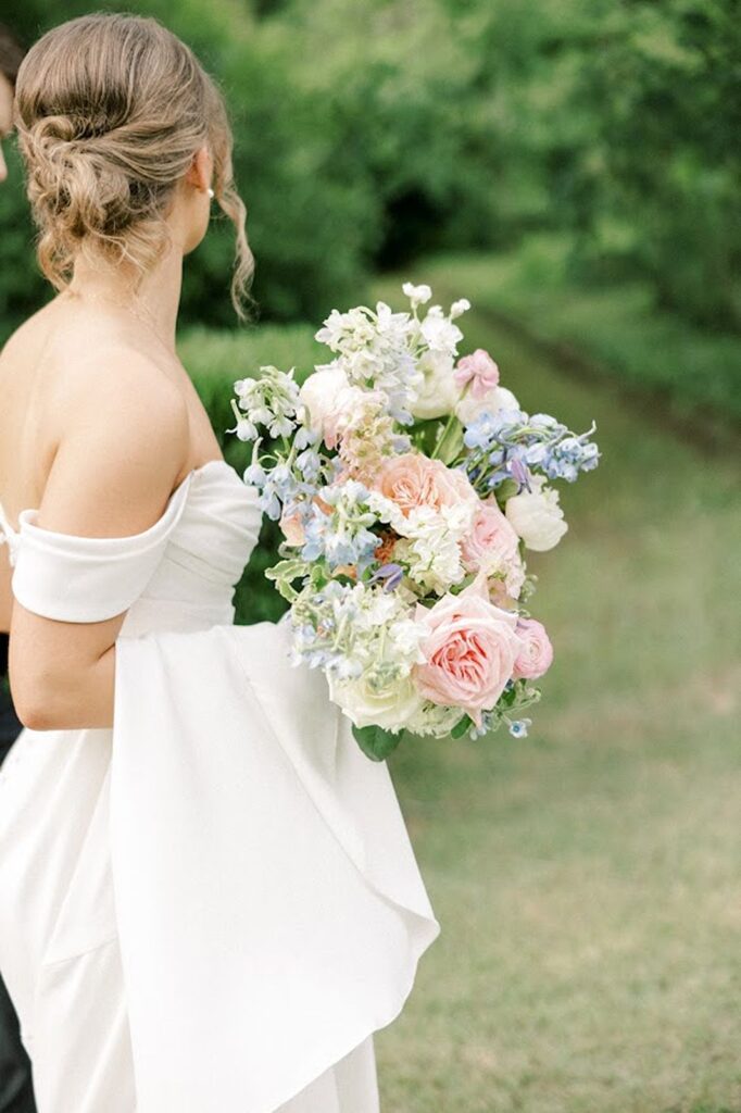 bride holding pink, green, and blue floral bouquet 