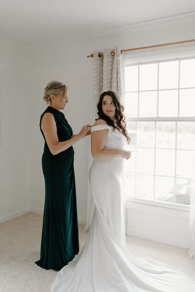 Mother helping bride into wedding dress