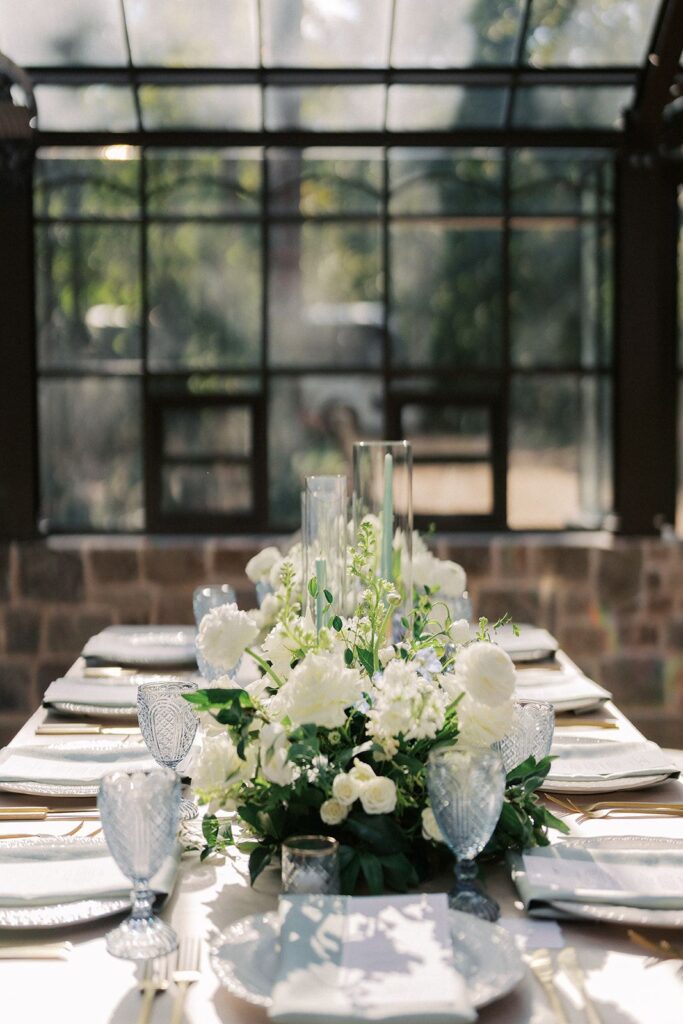 Table setting for wedding with florals, greenery, and blue glassware