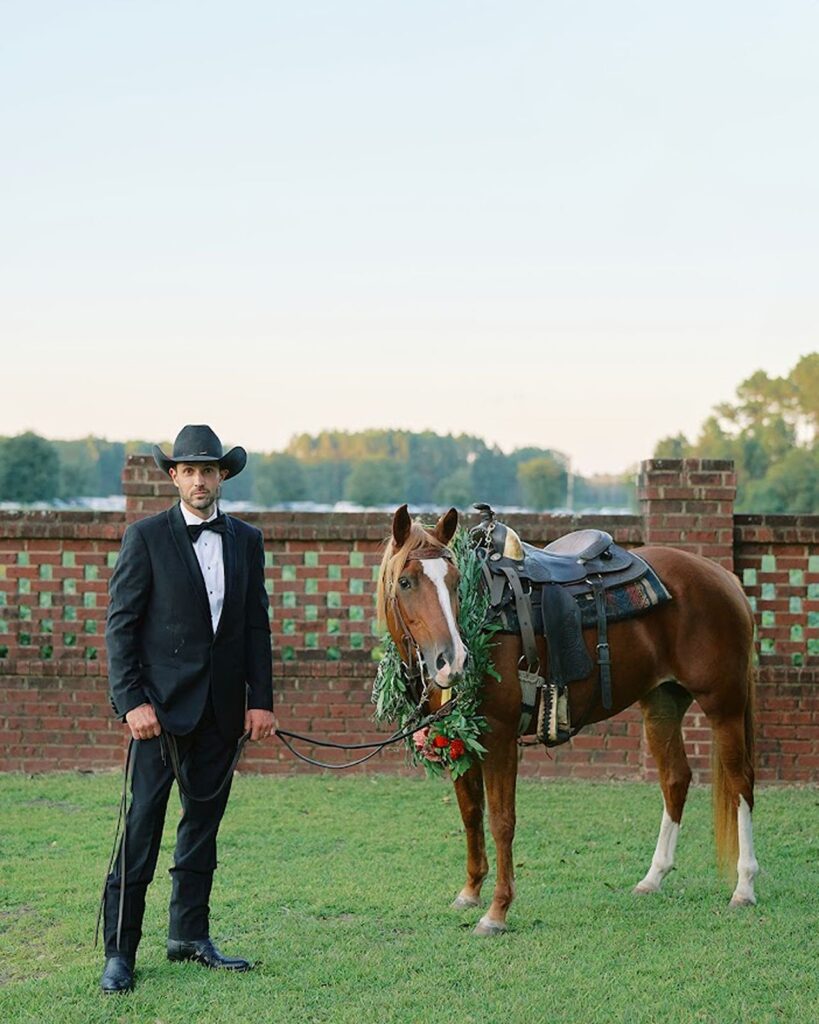 Groom posed with horse for countryside wedding