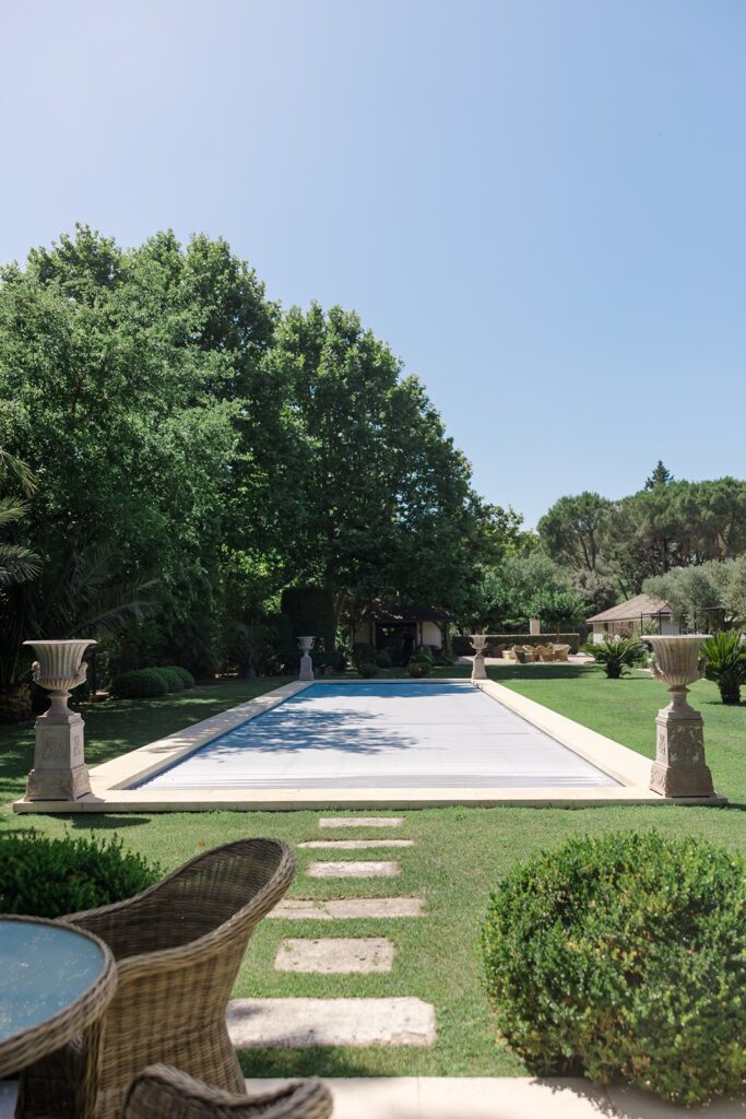 Elegant garden pool area surrounded by manicured lawns, tall trees, and classical stone urns an idyllic retreat in the French countryside