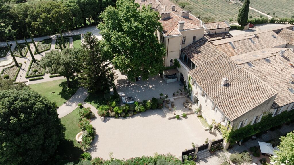 Charming aerial view of a French château courtyard, surrounded by lush gardens, stone paths, and timeless Provençal architecture