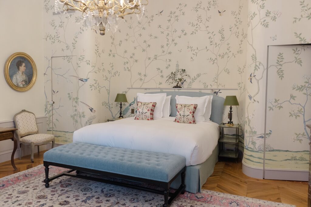 Charming château bedroom with elegant wallpaper, antique touches, and a serene French countryside feel