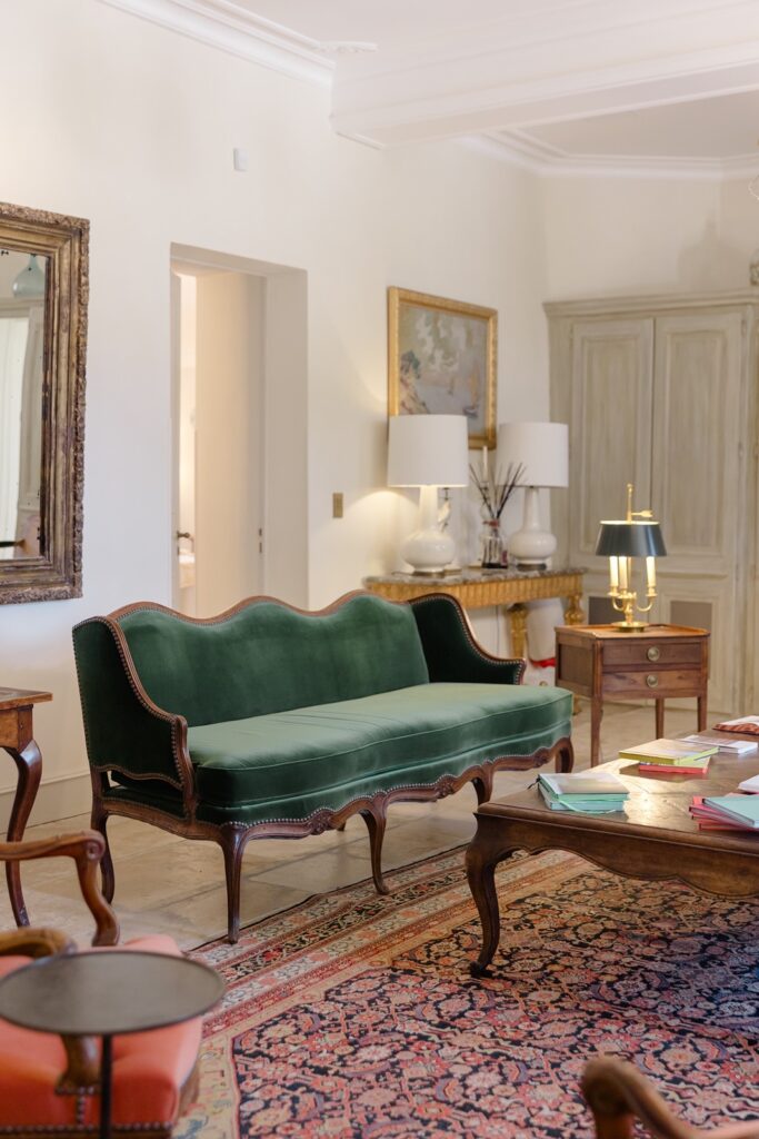 Elegant salon with vintage furnishings, a deep green velvet sofa, and refined French château charm