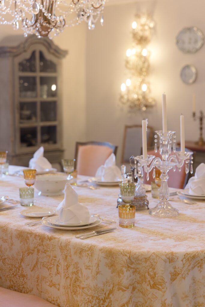 Romantic French dining room set with crystal chandeliers, fine china, and elegant candlelit ambiance