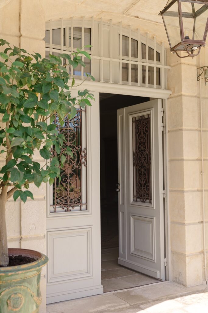 Charming château doorway with elegant wrought iron details and a welcoming touch of greenery