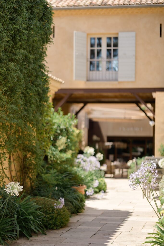 White shutters open to the summer sky, framed by stone walls and climbing greenery