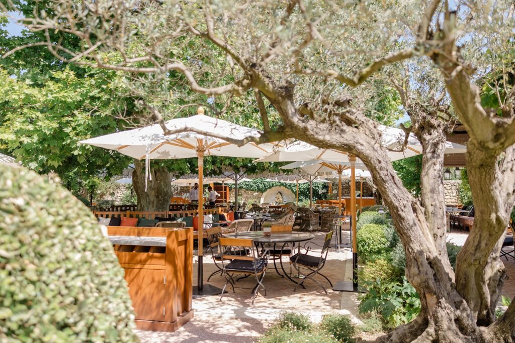 Charming outdoor dining terrace shaded by ancient trees and parasols, perfect for a relaxed celebration in the château gardens
