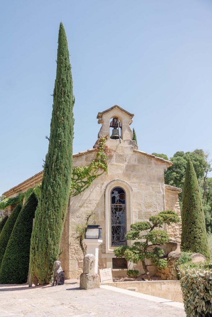 Charming stone chapel with stained-glass window, ivy accents, and a quaint bell tower—an idyllic setting for a French countryside wedding