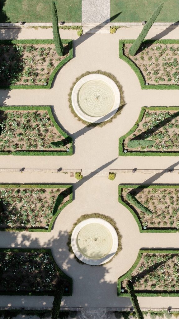 Symmetrical French garden with elegant fountains and perfectly manicured flowerbeds, viewed from above