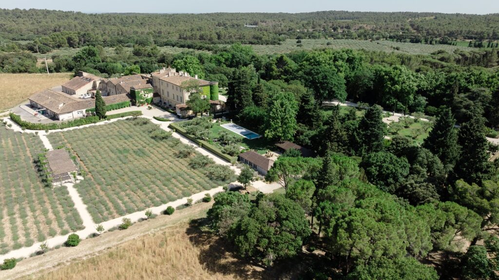 Breathtaking aerial view of a French château estate, surrounded by vineyards, gardens, and lush woodland in the Provençal countryside